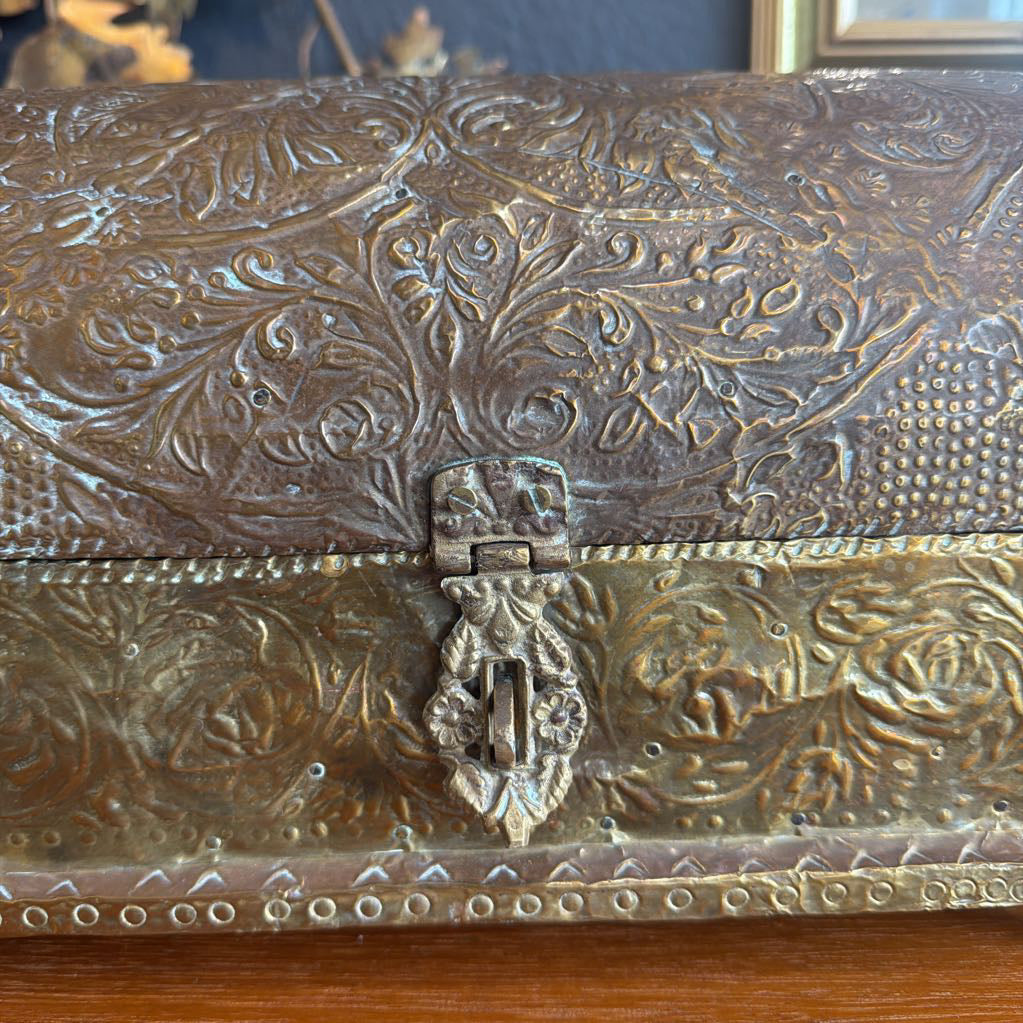 Decorative metal box with intricate patterns on a wooden surface