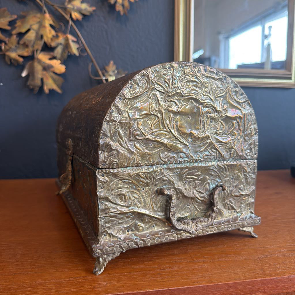 Decorative metal box with intricate designs on a wooden surface