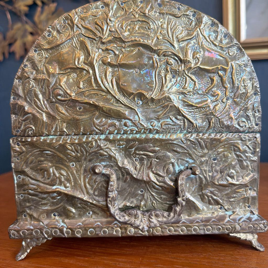 Decorative metal box with intricate designs on a wooden surface