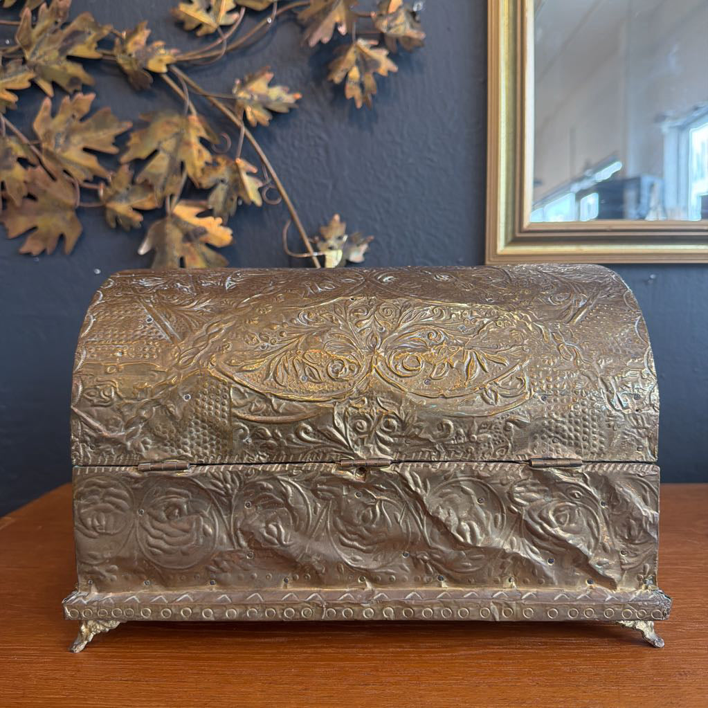Decorative metal chest with intricate designs on a wooden surface.