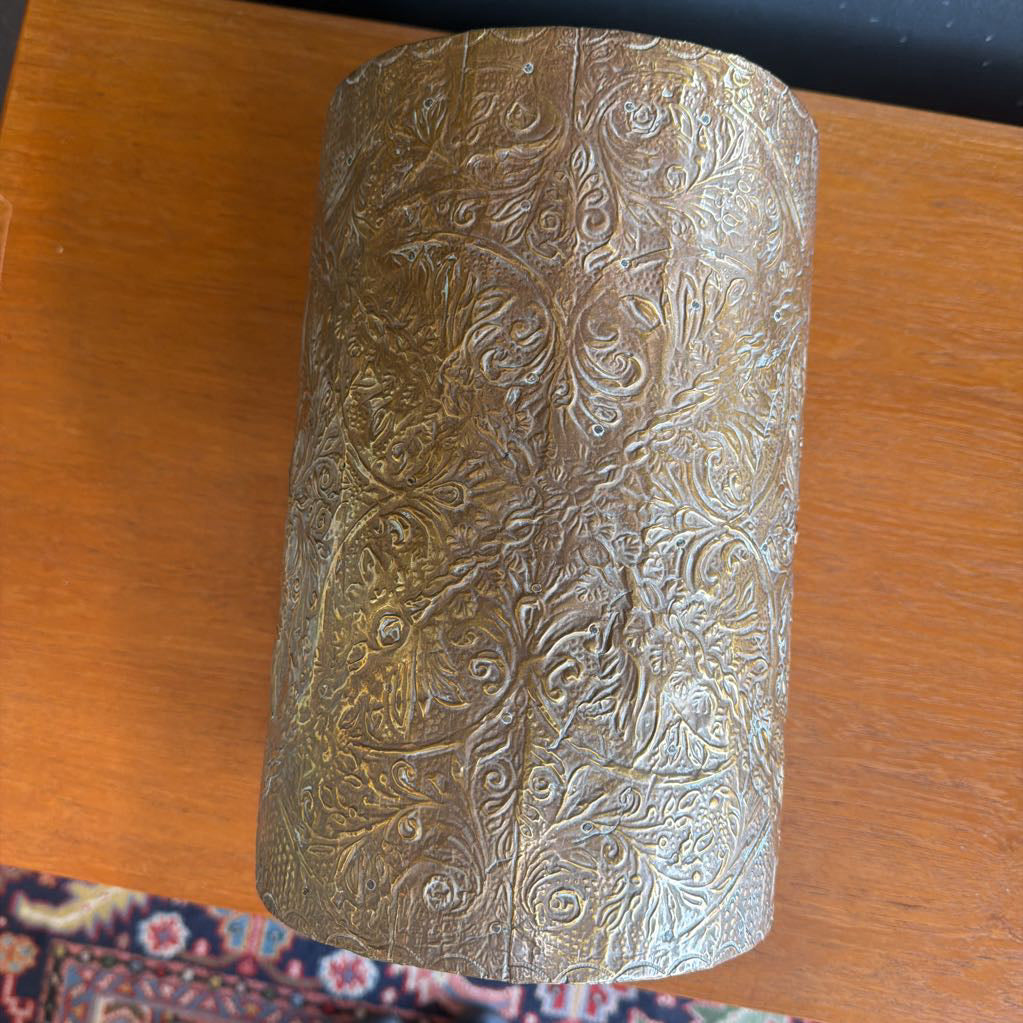 Decorative cylindrical object with intricate patterns on a wooden surface