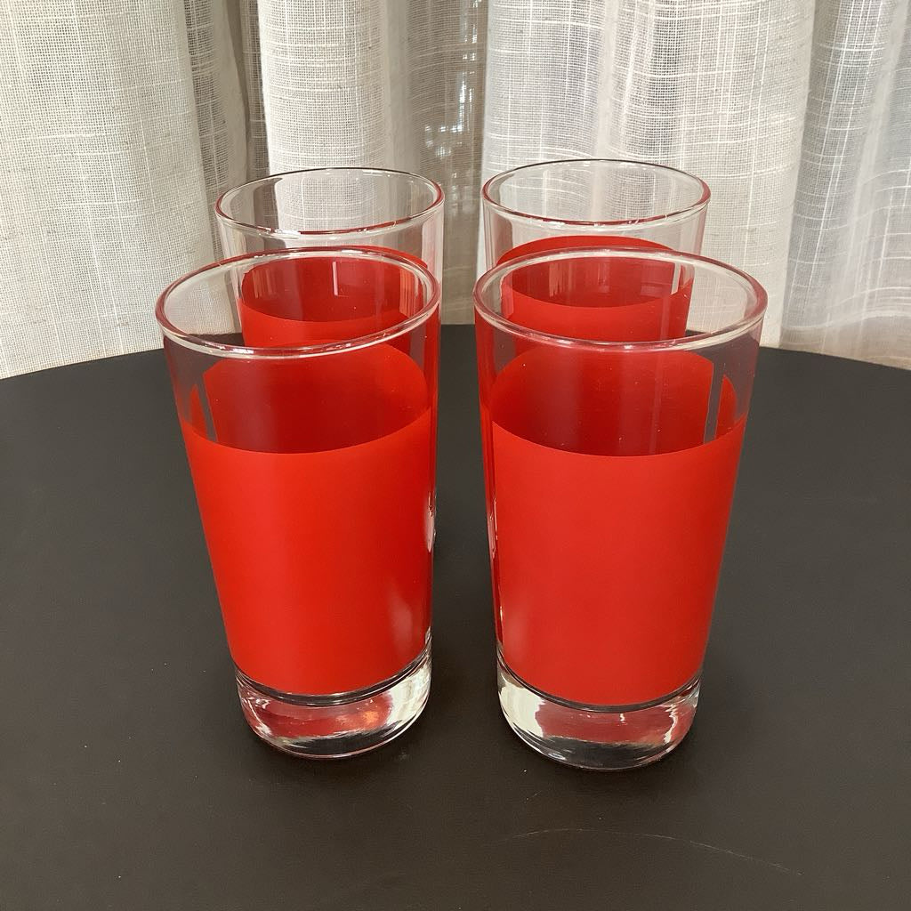Four clear glasses with red stripe on a dark surface and light curtain background
