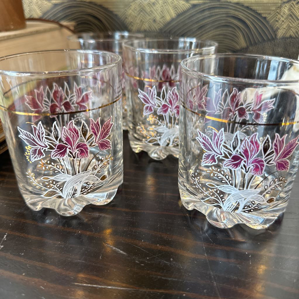 Set of four floral-patterned glass tumblers on a wooden surface