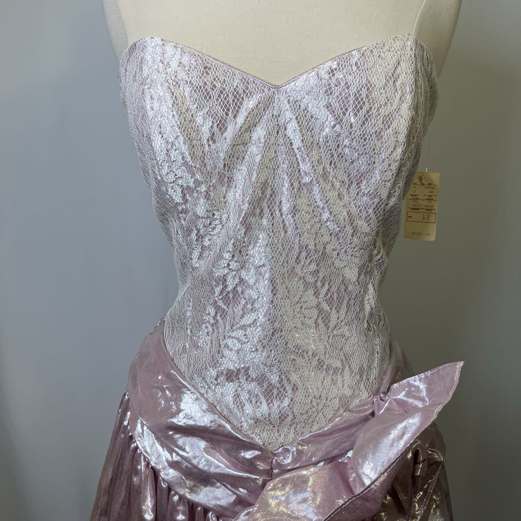 Mannequin wearing a pink lace top and skirt with a tag on a plain background