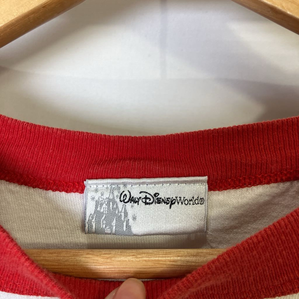 Close-up of a red shirt with a Disney World label on a wooden hanger.