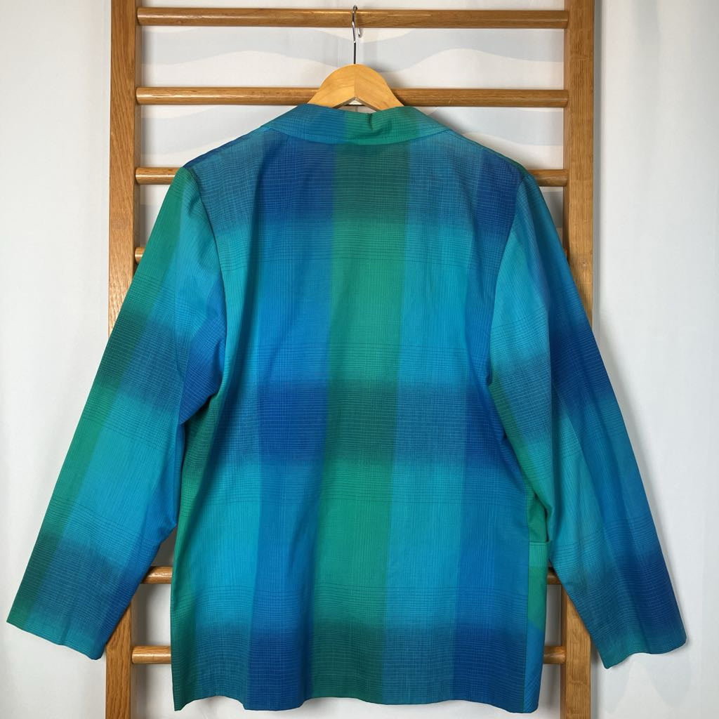 Blue and green gradient jacket on a wooden hanger against a white wall.