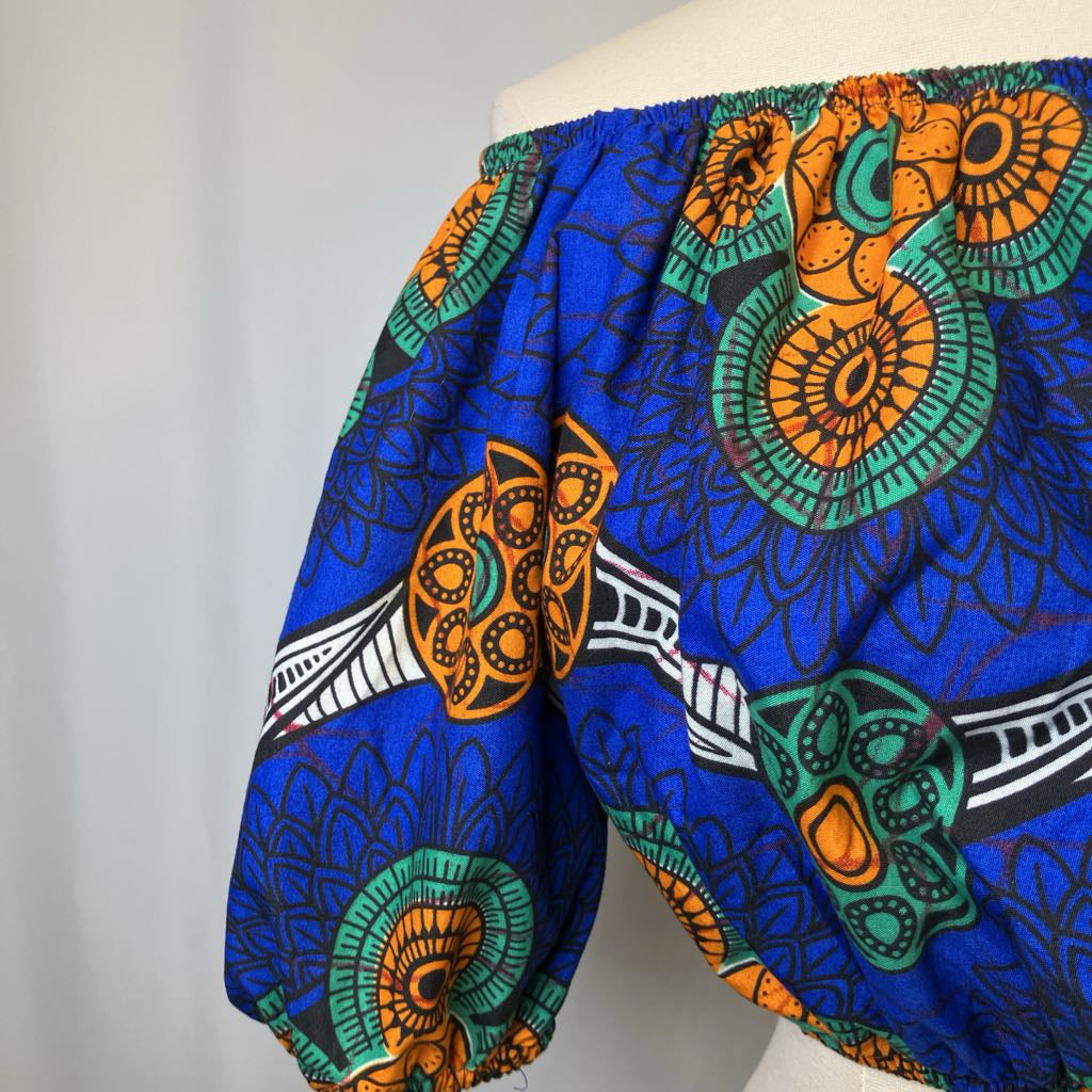 Blue off-shoulder top with colorful geometric pattern on a white background