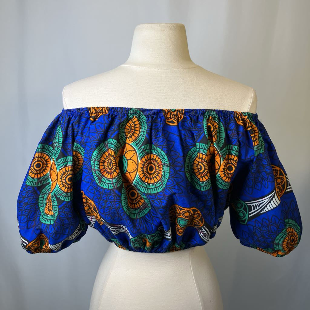 Blue off-shoulder top with colorful patterns on a mannequin against a gray background