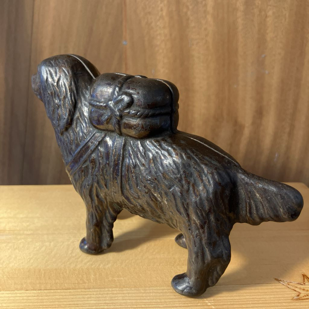 Bronze statue of a dog with a bow on a wooden surface