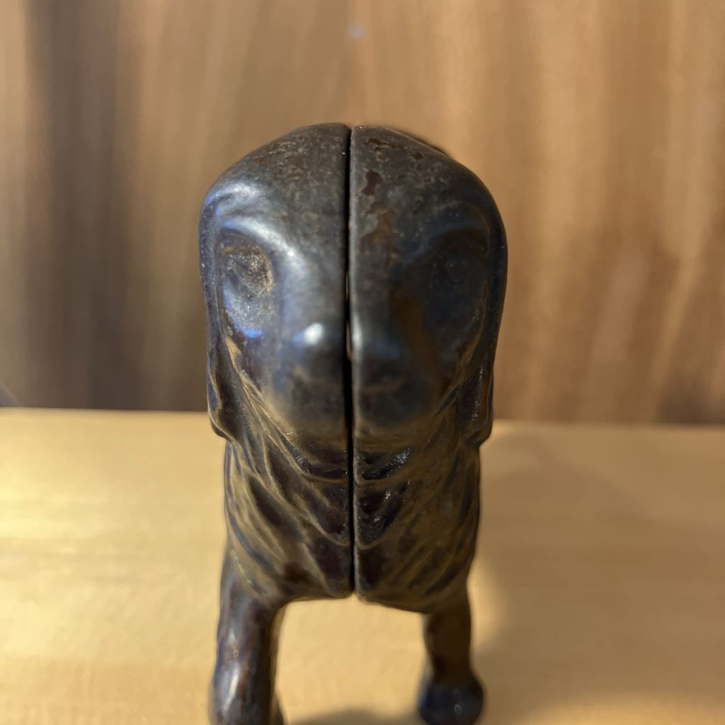 Bronze sculpture of a dog on a wooden surface with a blurred background
