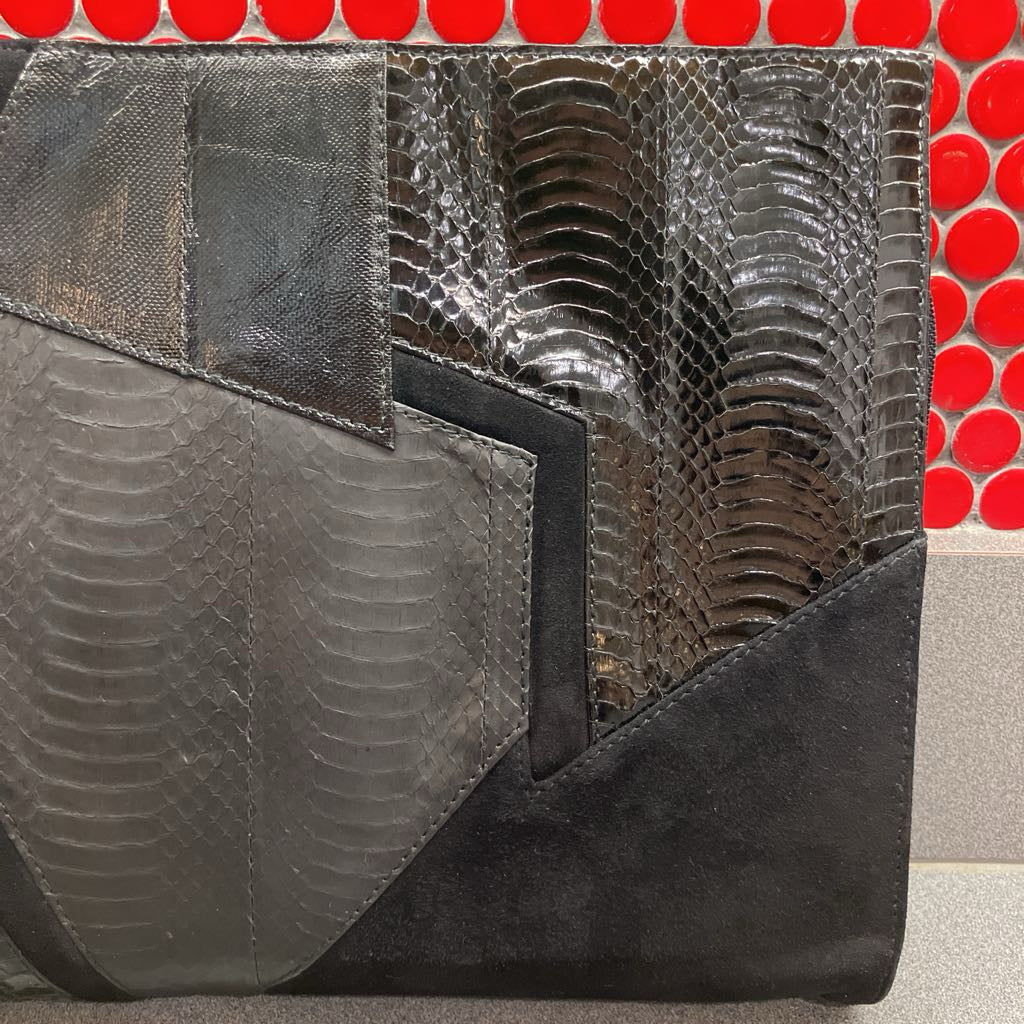 Black and gray textured clutch bag with a red and white patterned background