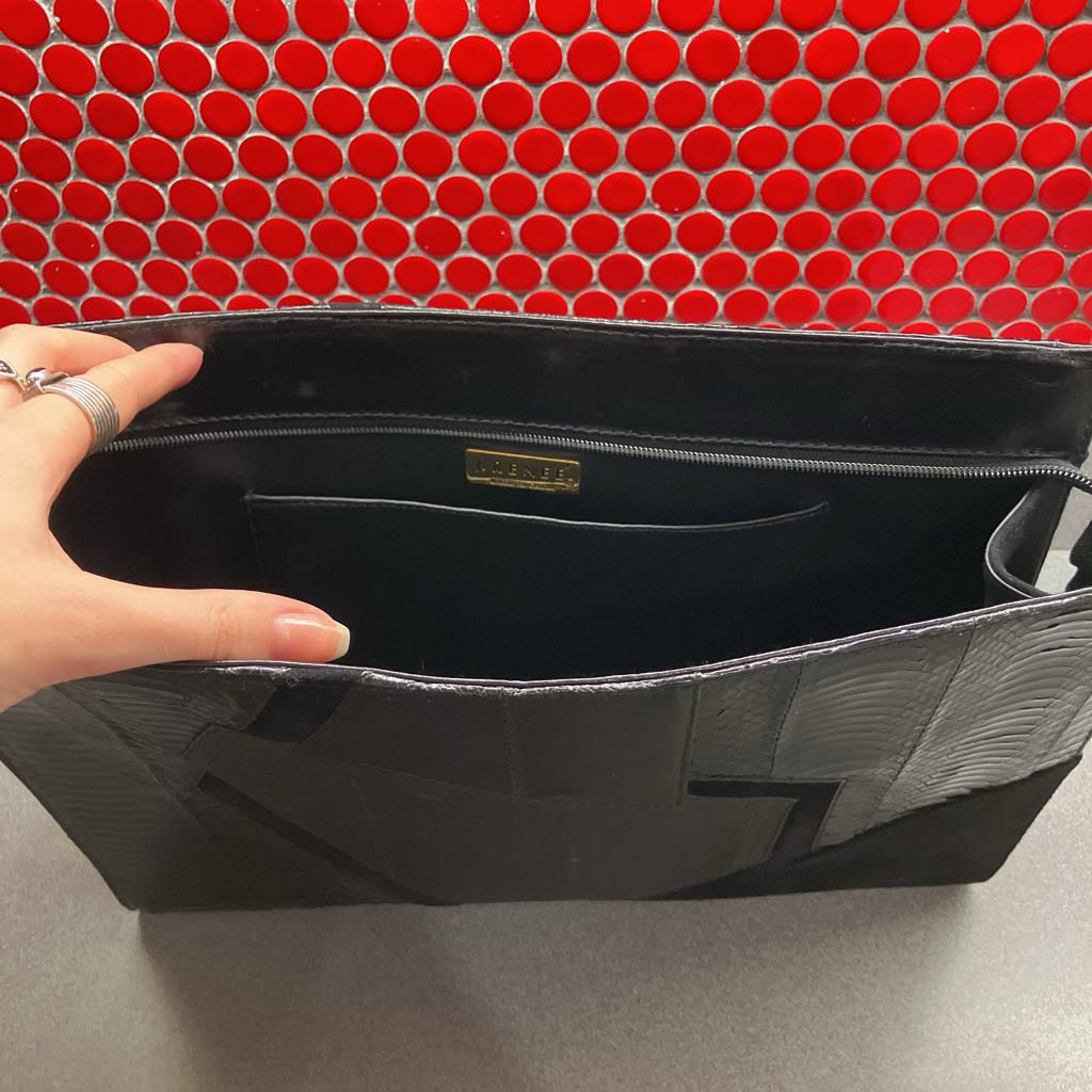Black handbag with a visible brand logo against a red circular patterned background