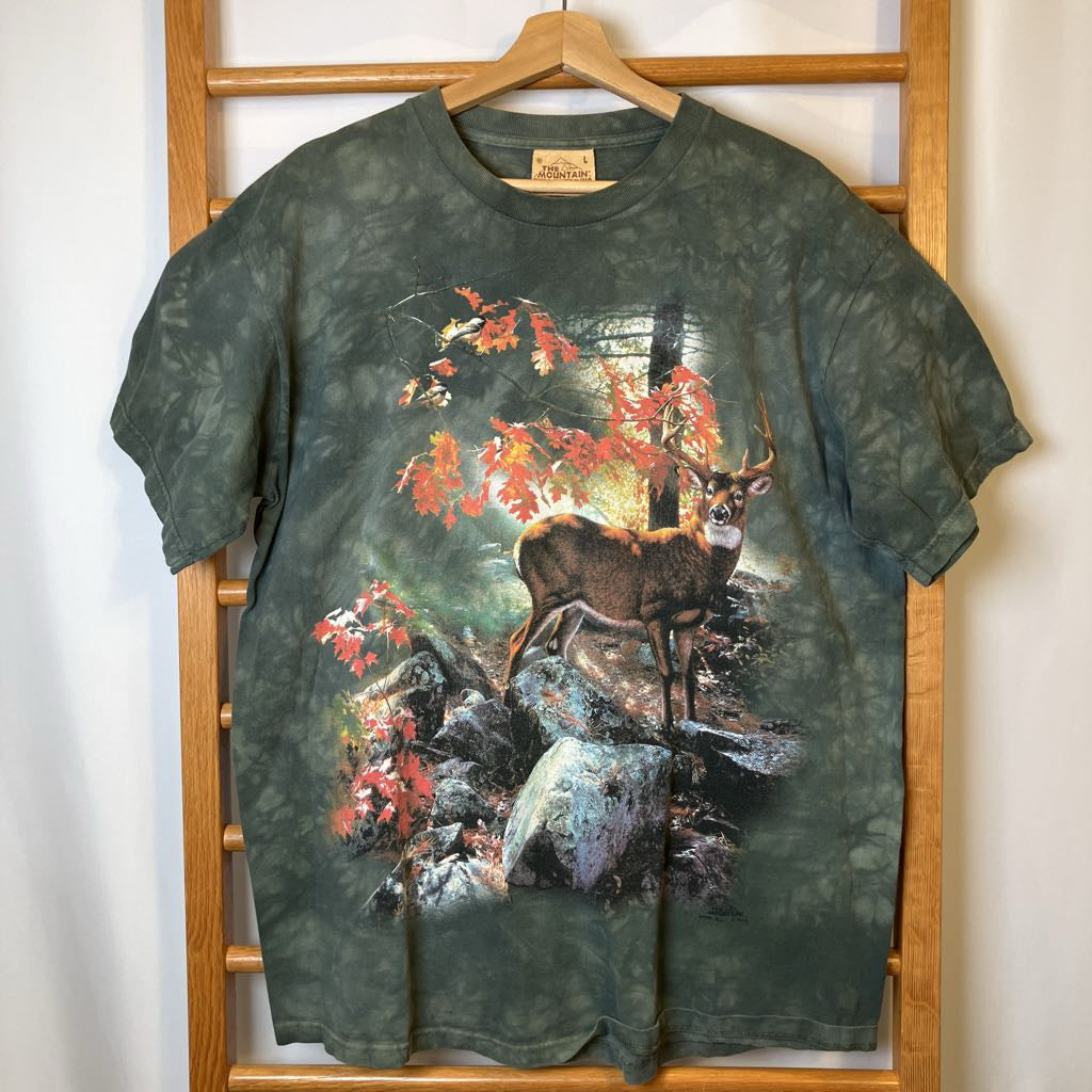 T-shirt with a deer graphic on a wooden hanger against a white wall