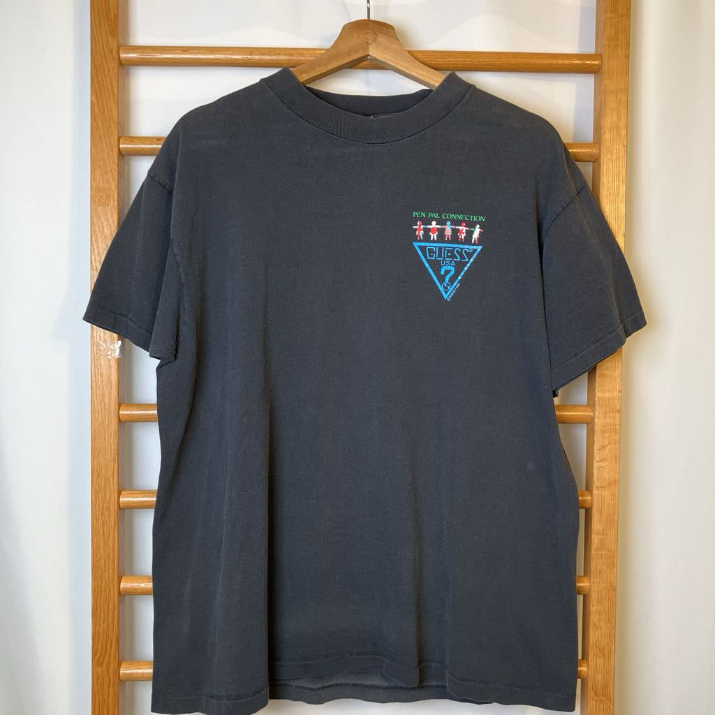 Black t-shirt with a logo on a wooden hanger against a white wall