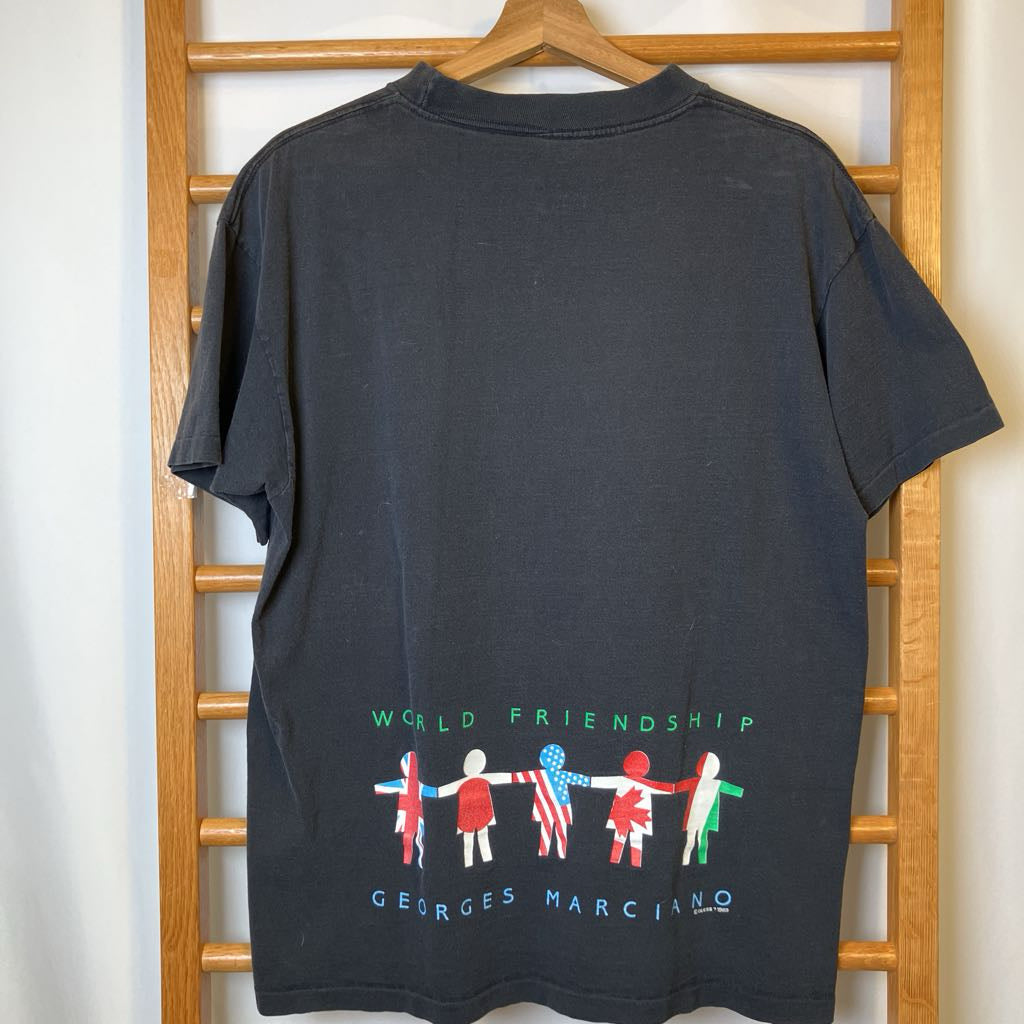 Black t-shirt with colorful graphic design on a wooden hanger against a white wall