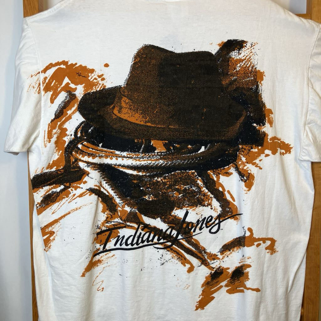 White t-shirt with a graphic of a hat and lasso on the back, featuring the text 'Indiana Jones'.