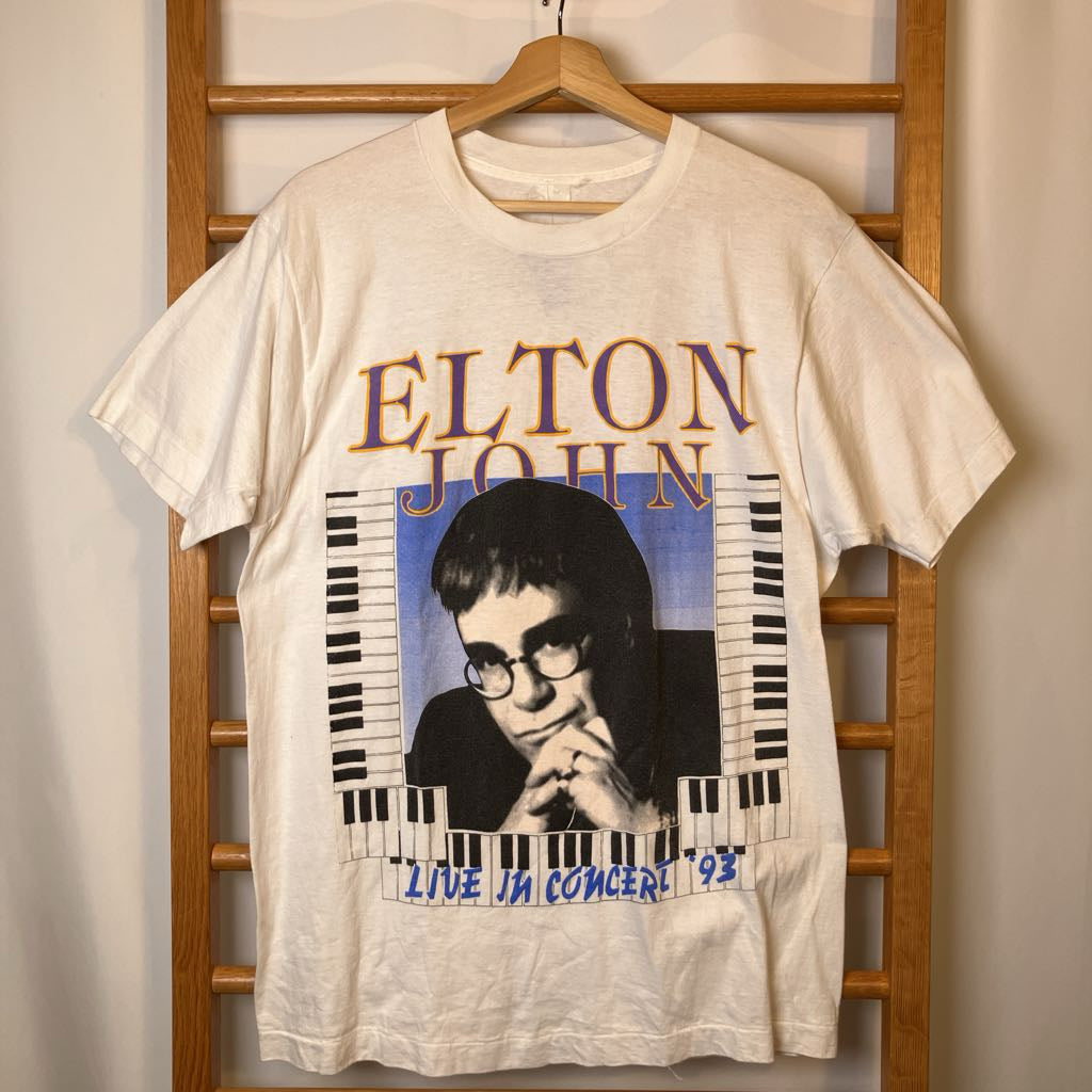 Vintage Elton John t-shirt with a graphic of the artist and text 'Elton John Live in Concert '93' on a wooden hanger.