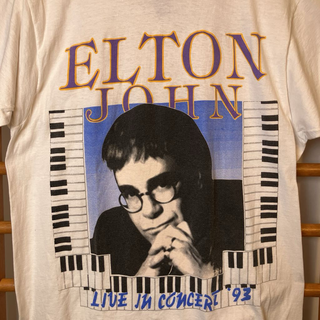 T-shirt with Elton John graphic and text on a beige background