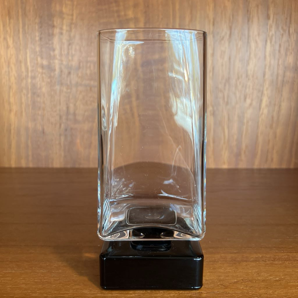 Clear bar glass with black base on a wooden surface