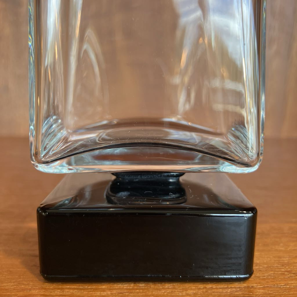 Clear bar glass with black base on a wooden surface