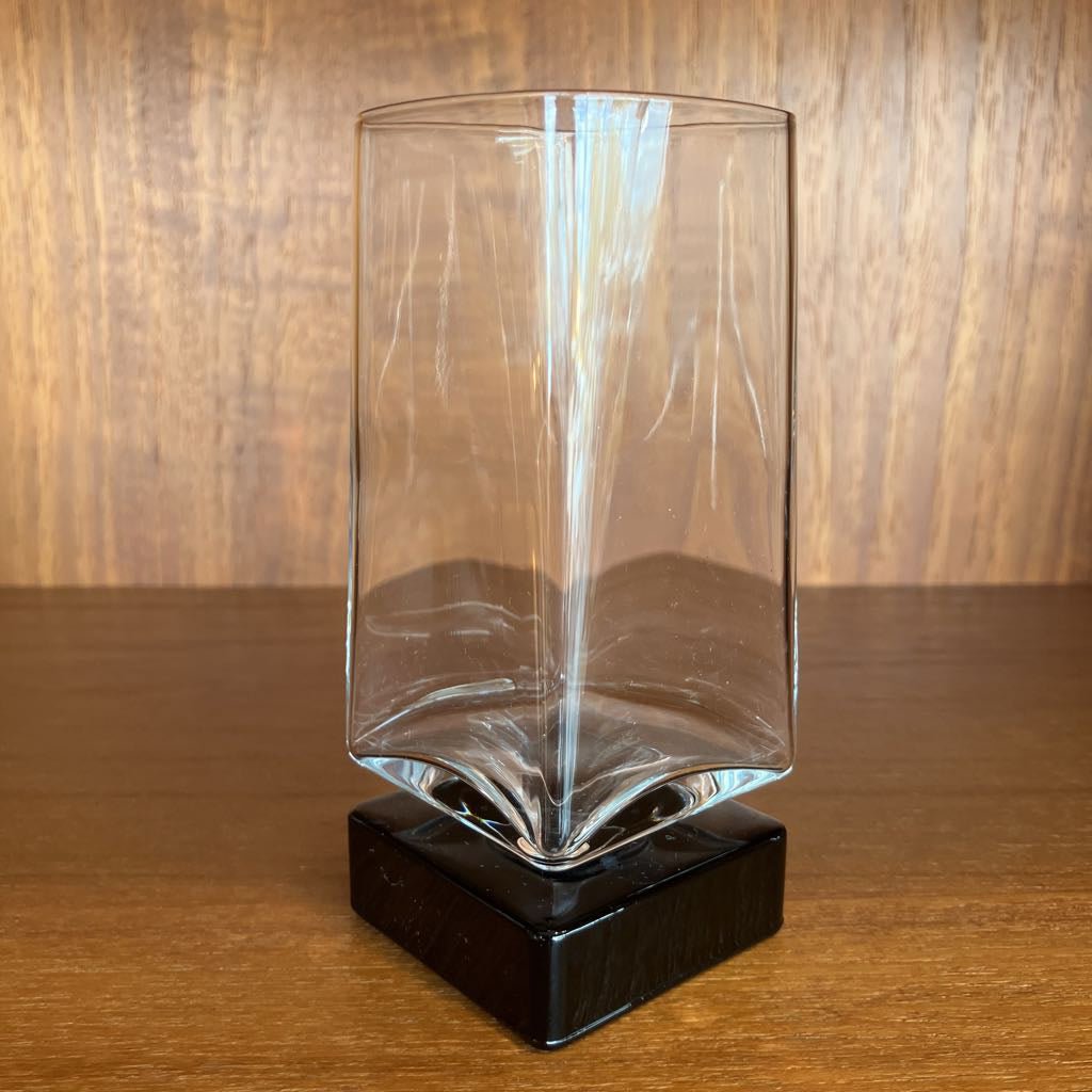 Clear bar glass on a black base against a wooden background