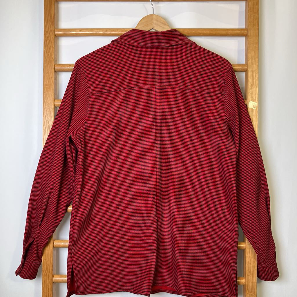 Red checkered shirt on a wooden hanger against a white wall