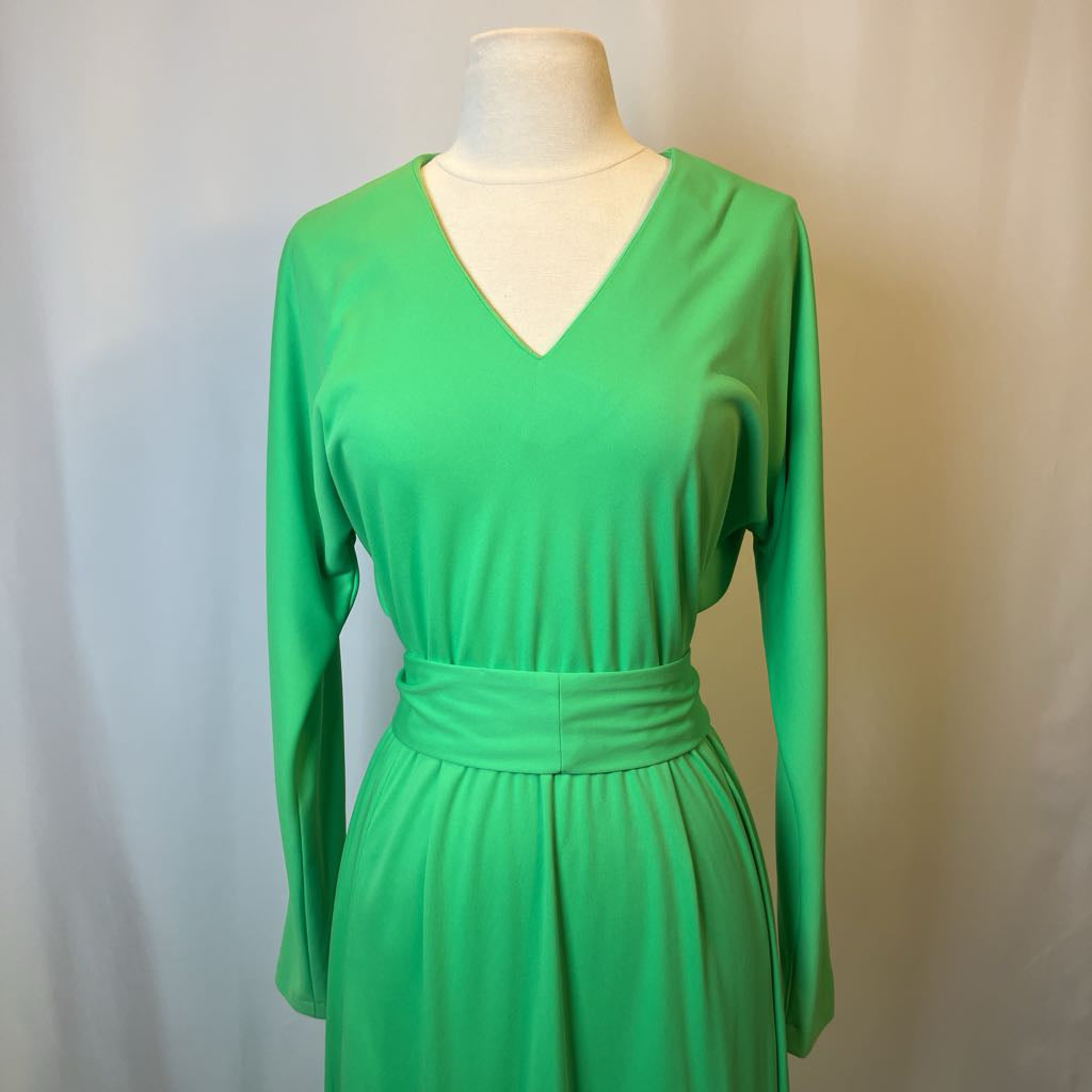 Green dress on a mannequin against a plain background