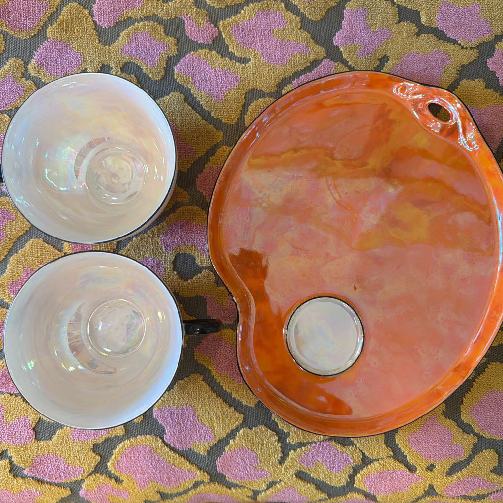 Two white ceramic bowls and an orange ceramic plate on a patterned surface