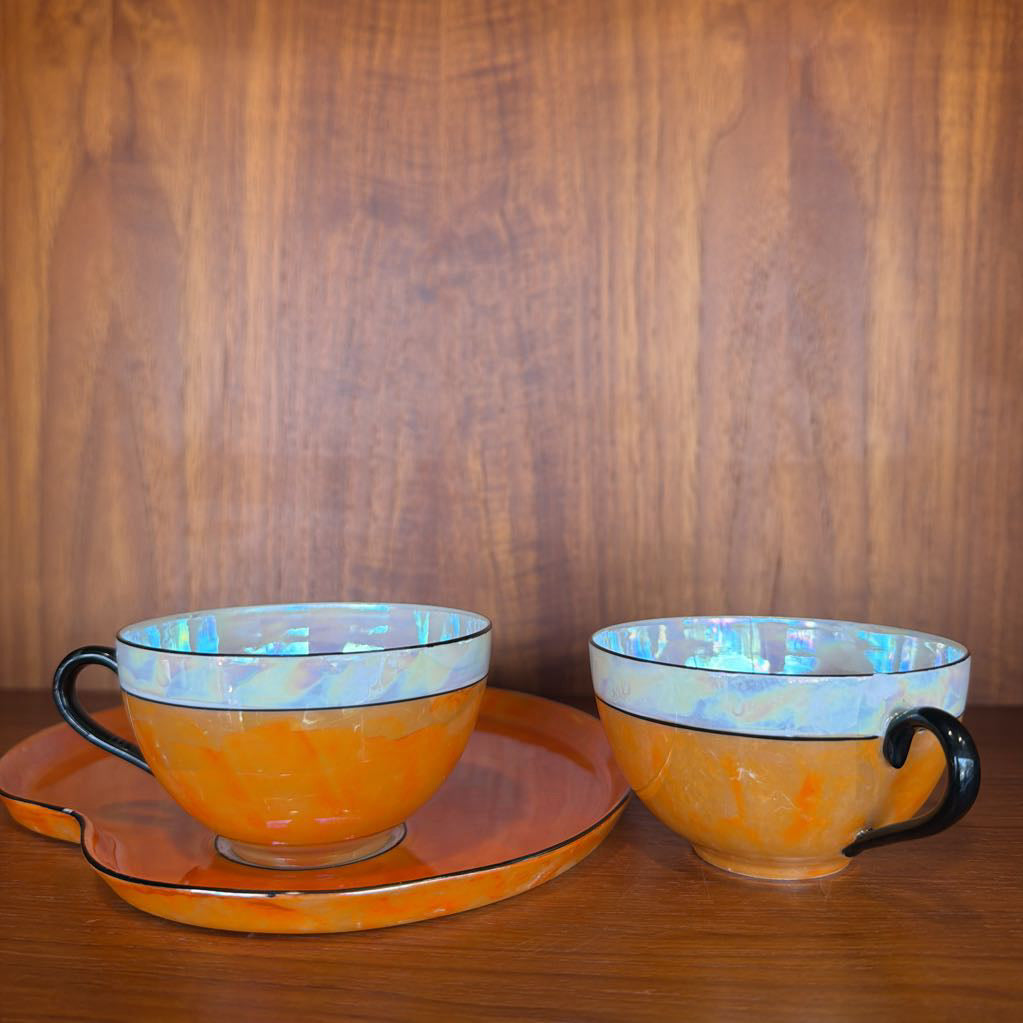 Two ceramic teacups with black handles on a wooden surface and background.