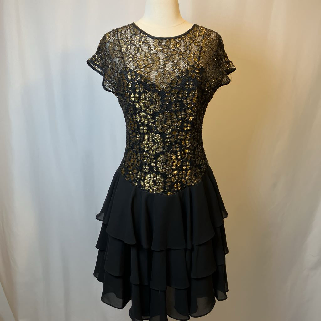 Black lace dress on a mannequin against a plain background
