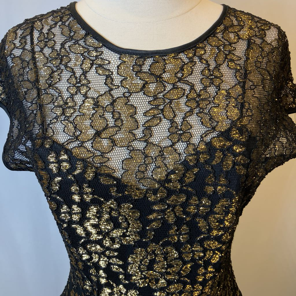 Black lace top with gold floral patterns on a mannequin against a neutral background