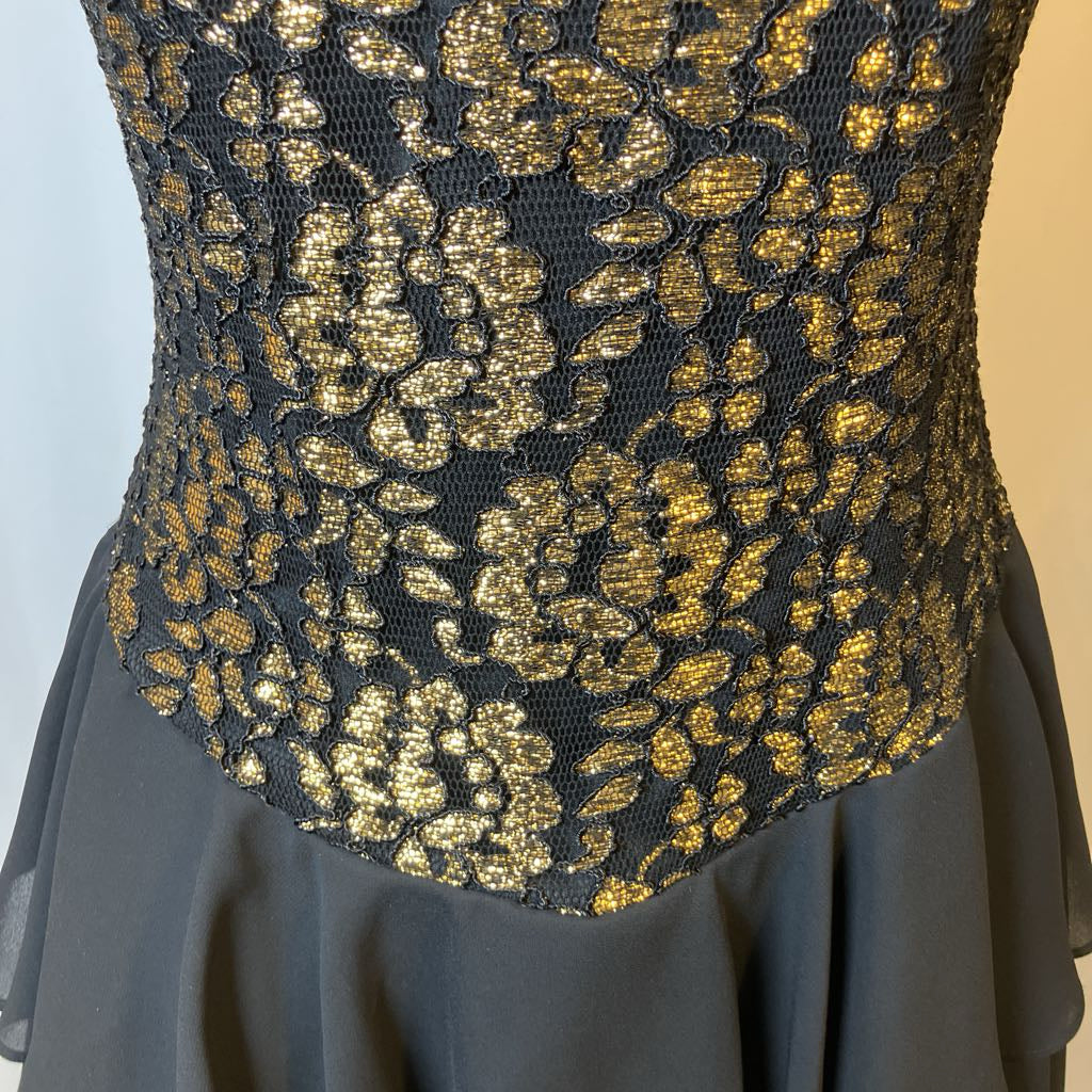 Black dress with gold floral lace detailing on a neutral background
