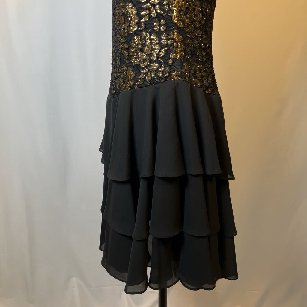 Black dress with gold lace top on a mannequin against a white background