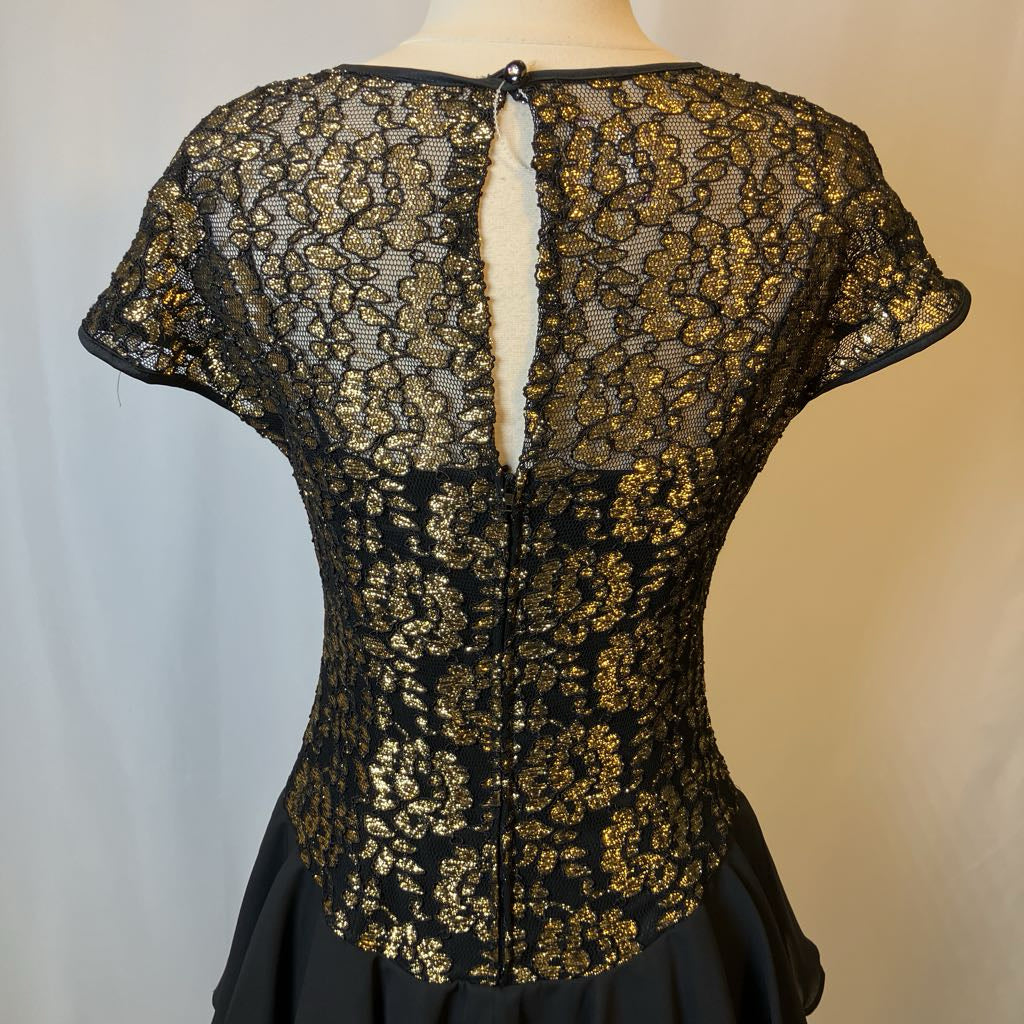 Black lace top with gold detailing on a mannequin against a neutral background