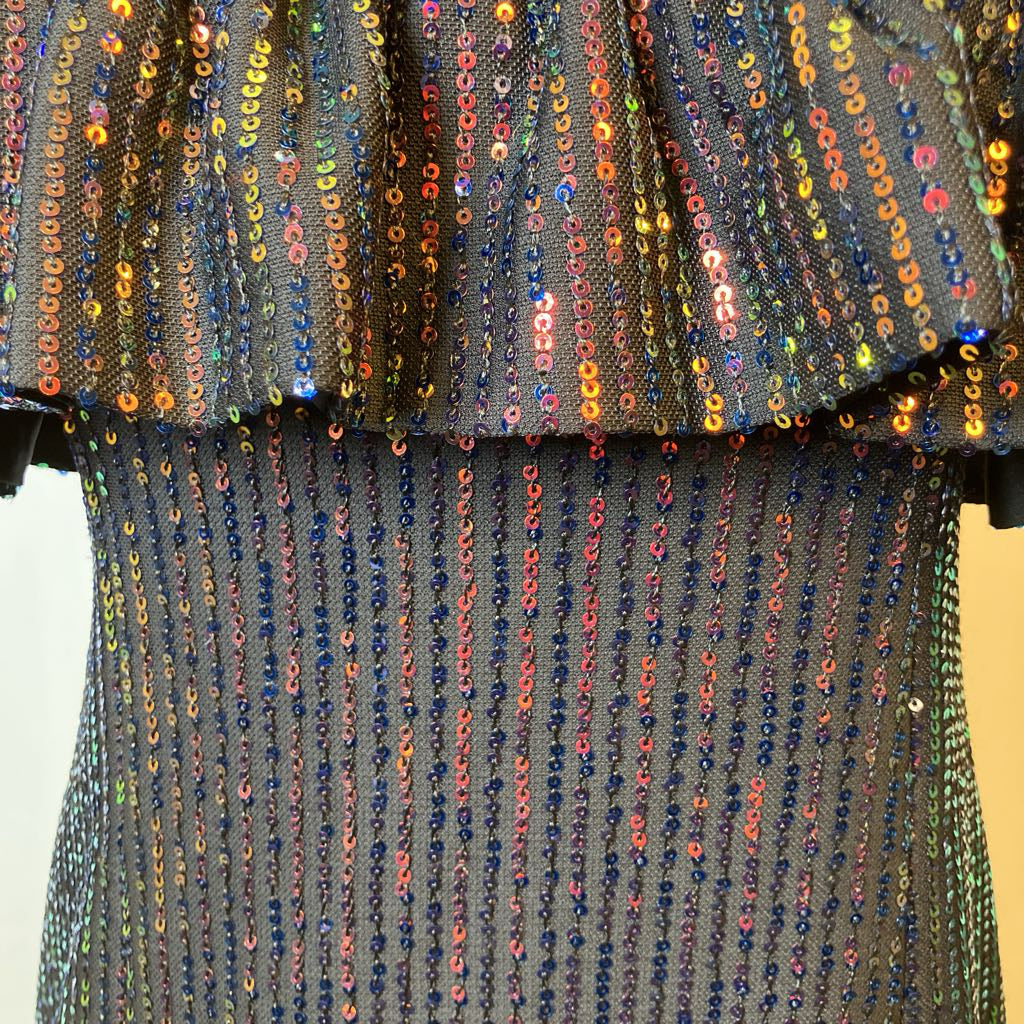 Close-up of a sequined fabric with multicolored beads on a plain background