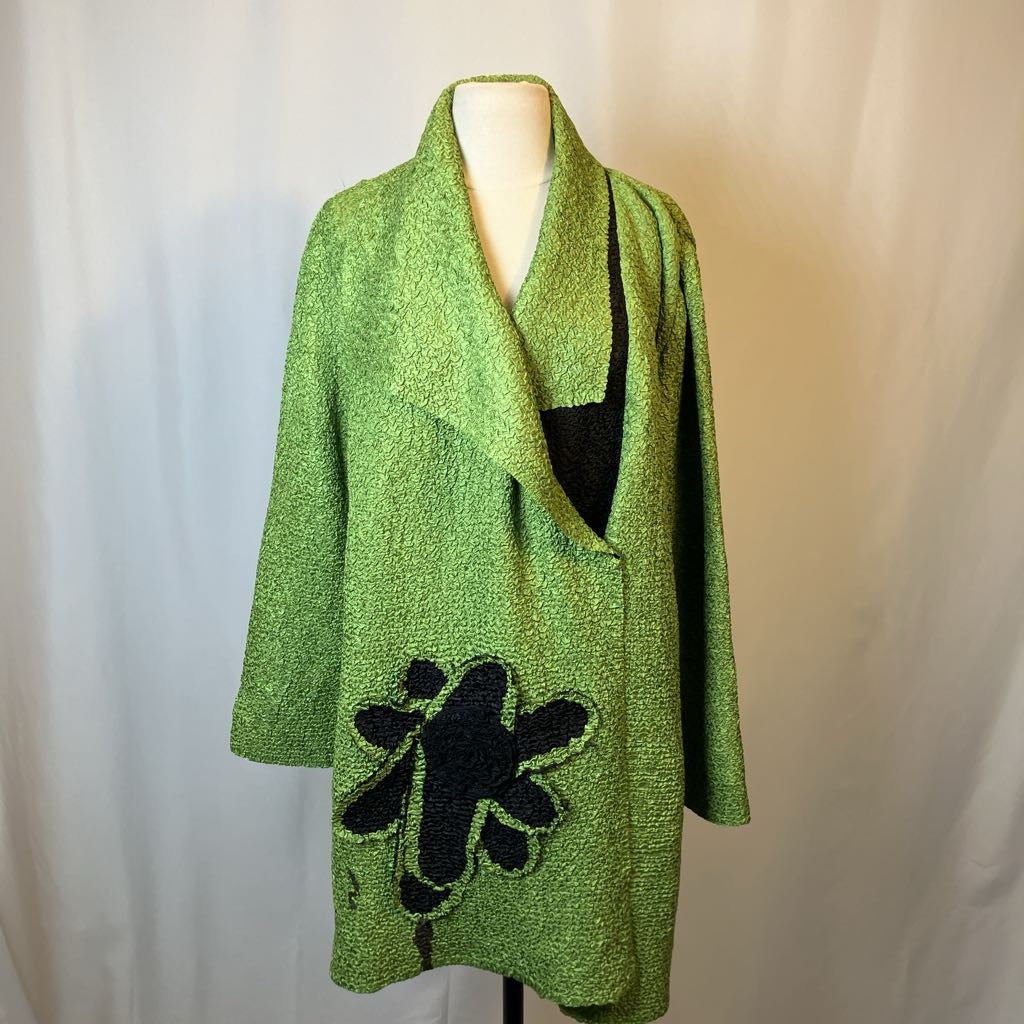 Green cardigan with black floral design on a mannequin against a plain background