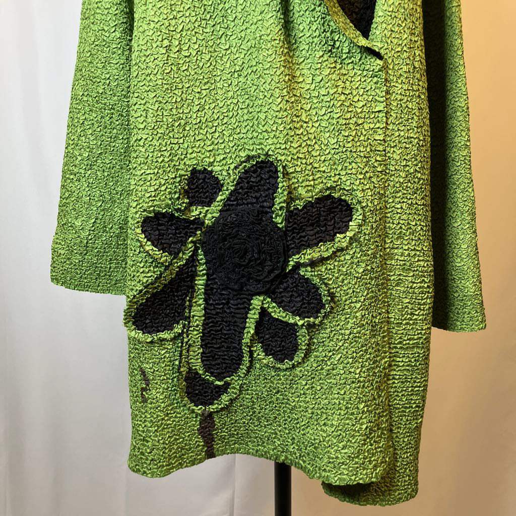 Green textured jacket with black floral design on a mannequin against a neutral background