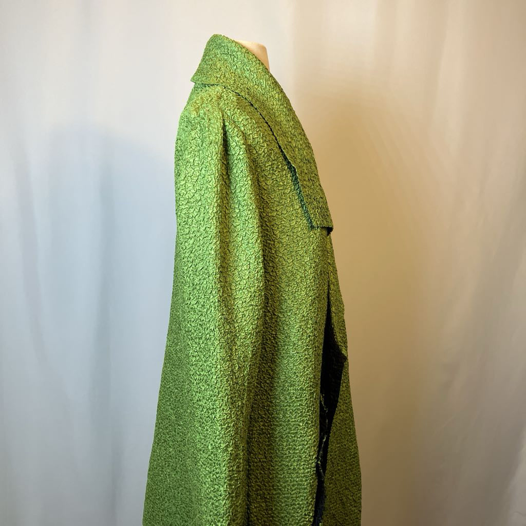 Green textured garment on a mannequin against a plain background