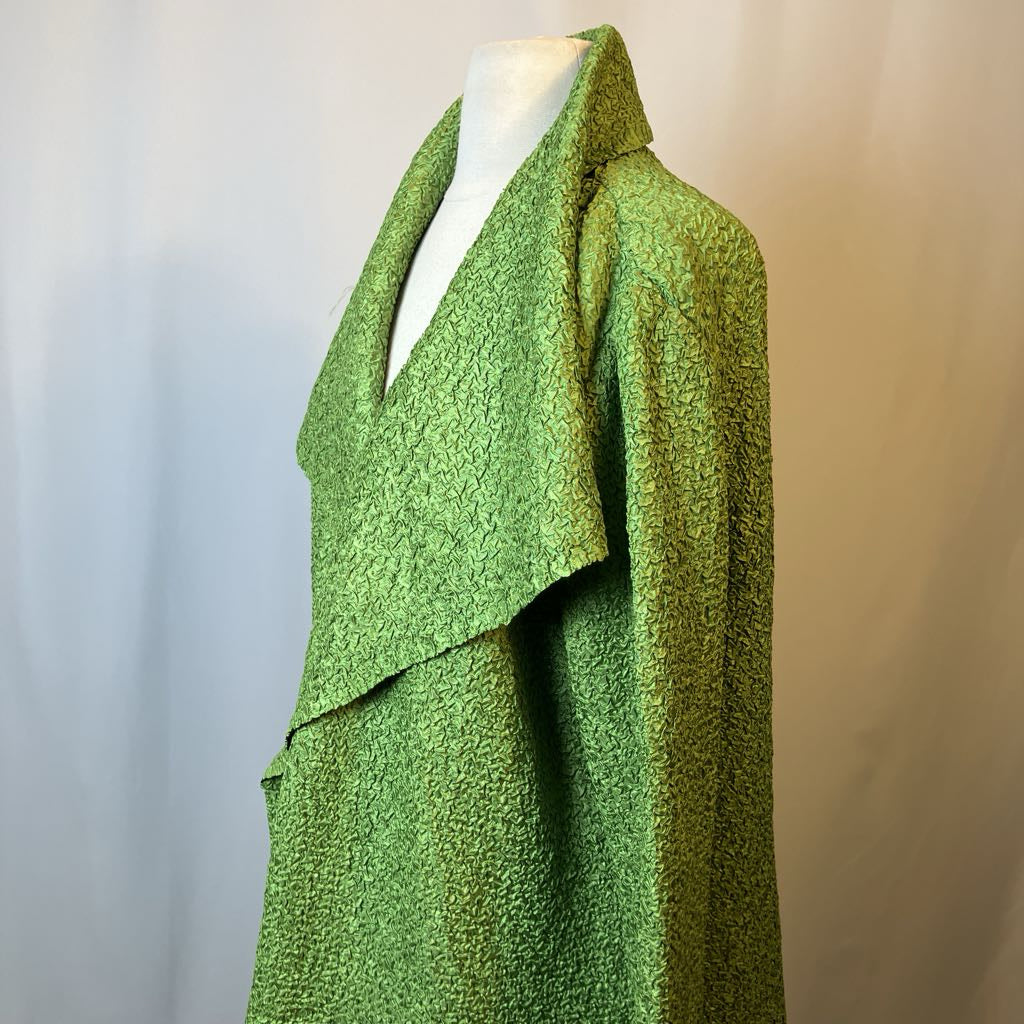 Green textured dress on a mannequin against a neutral background