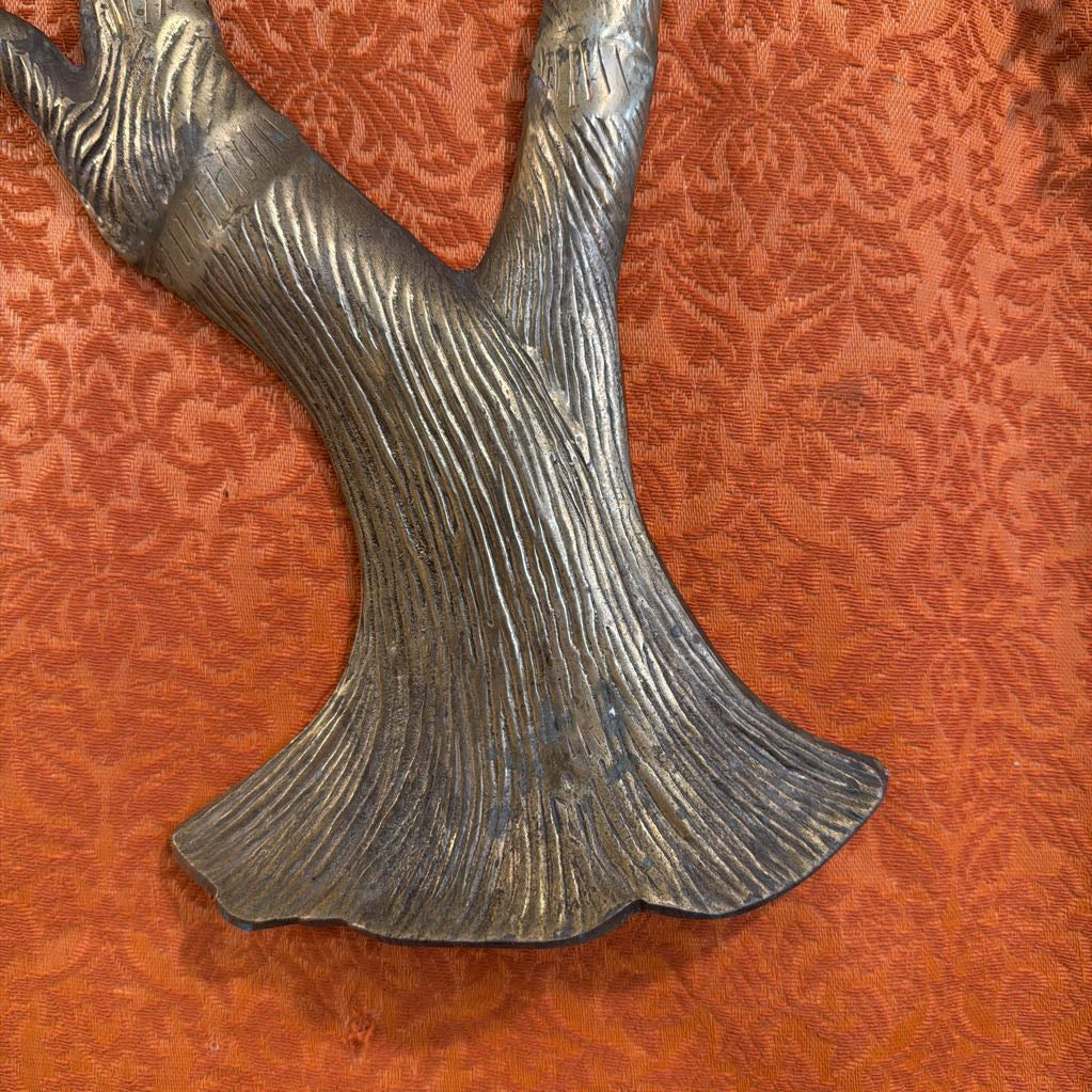Metallic tree branch sculpture on a textured orange background