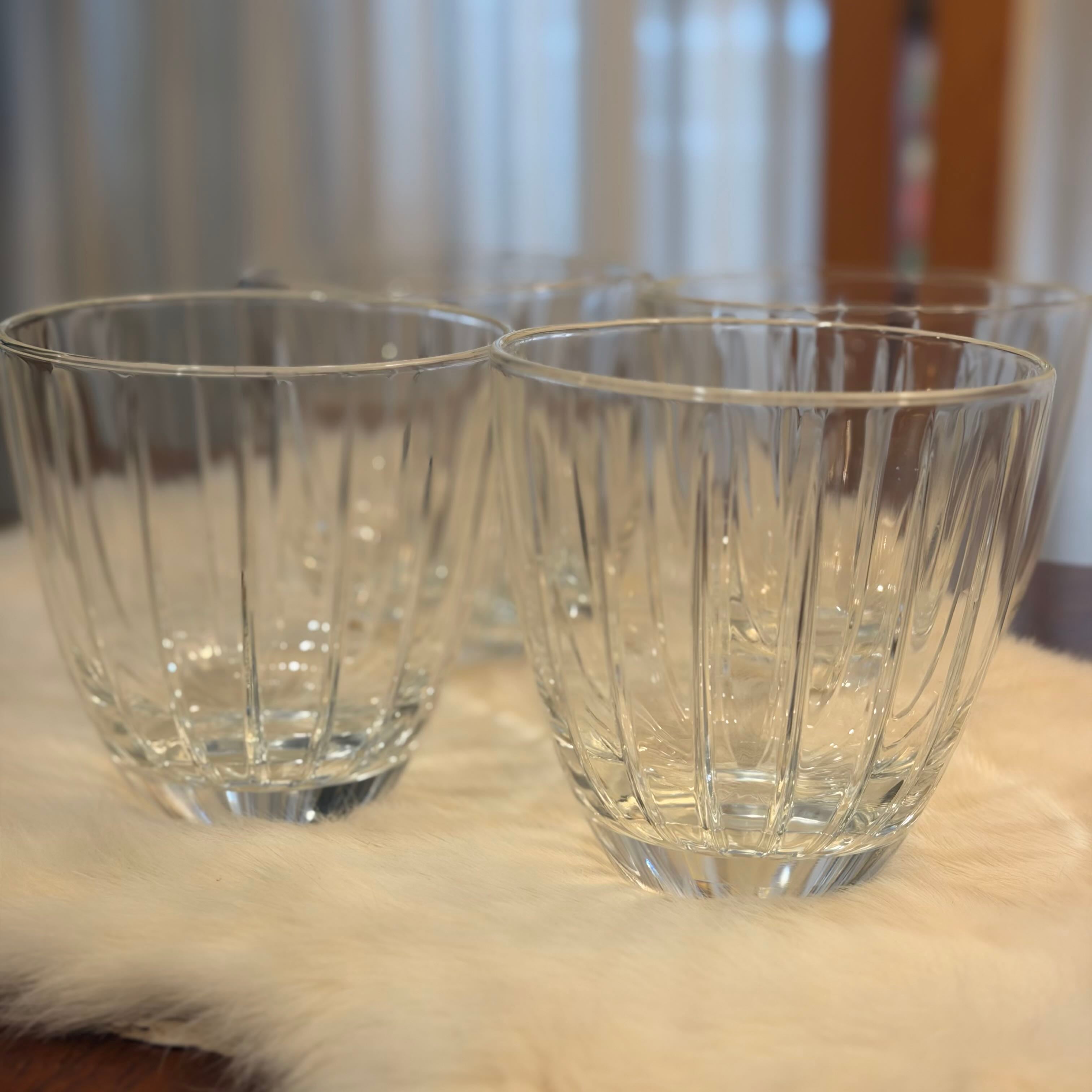 Two clear glass tumblers on a fur surface with a blurred background