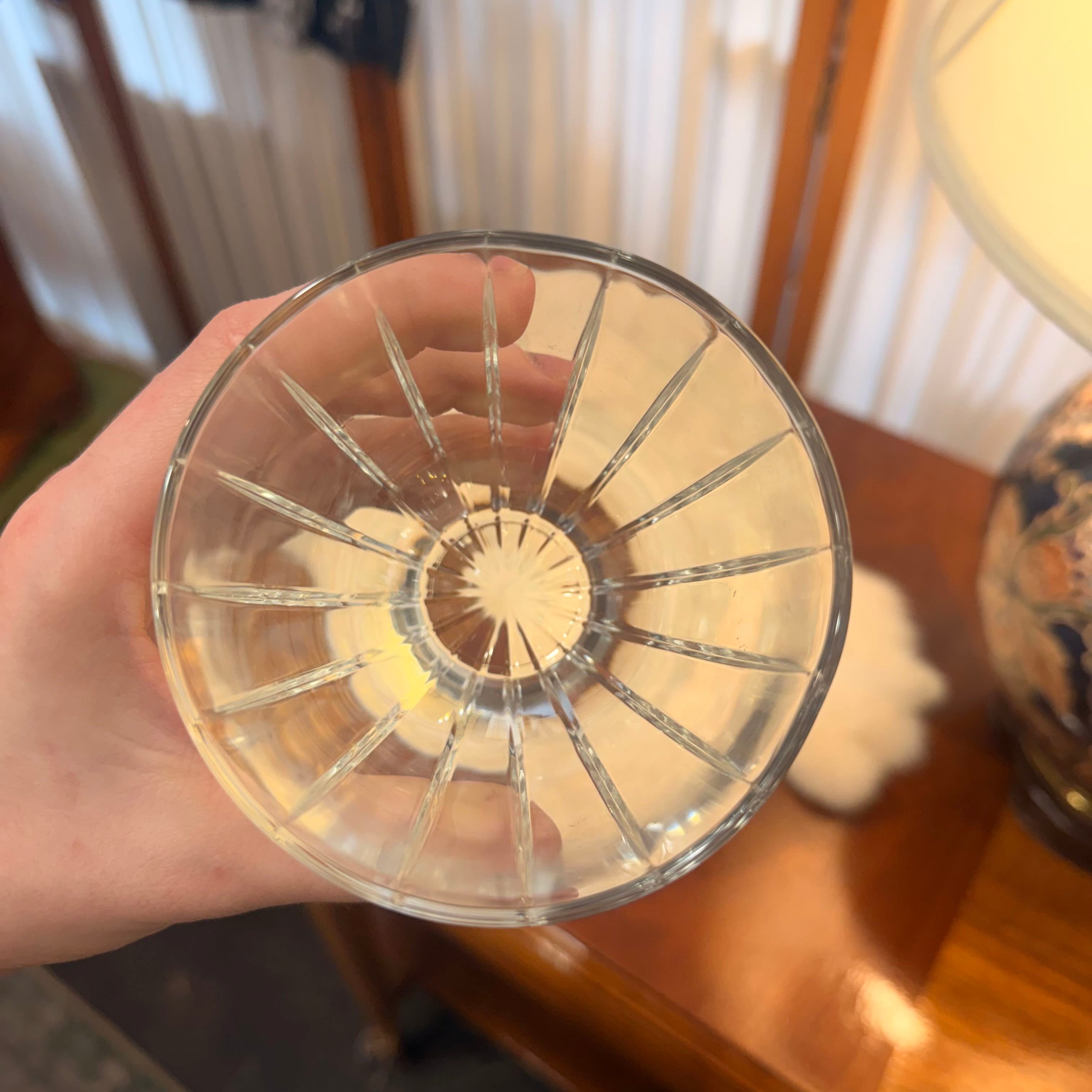 Clear glass with starburst pattern held by a hand in an indoor setting