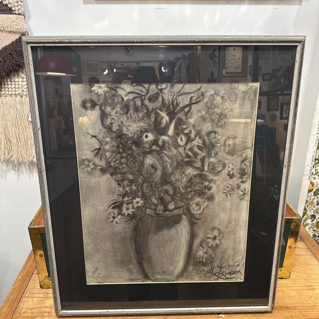 Framed black and white artwork of a floral arrangement on a wooden surface.