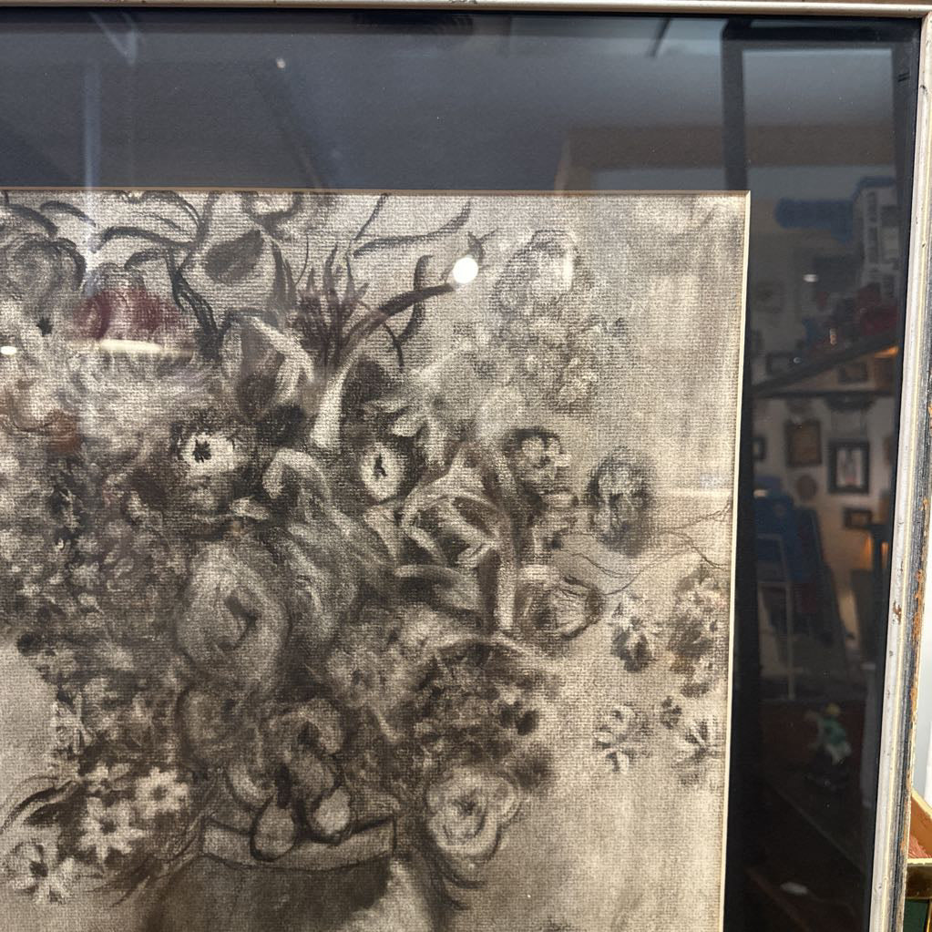 Decorative fabric with floral patterns in a frame, with a blurred indoor background.