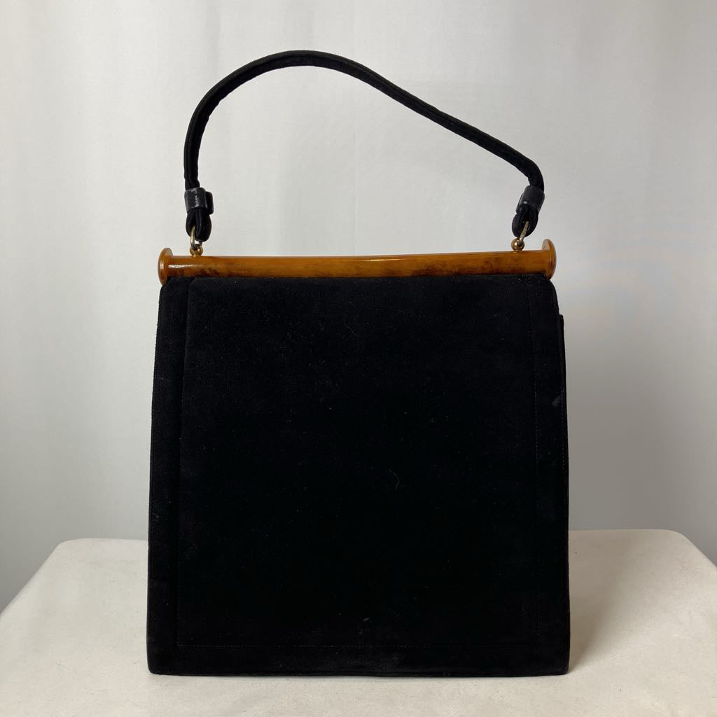 Black handbag with a lucite handle on a white surface