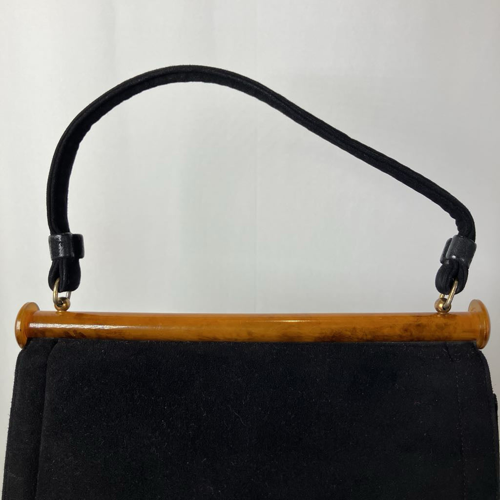 Black handbag with a lucite handle on a white background