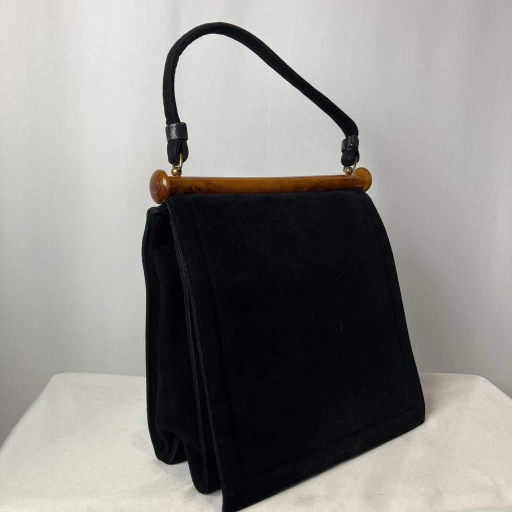 Black handbag with a lucite handle on a white surface