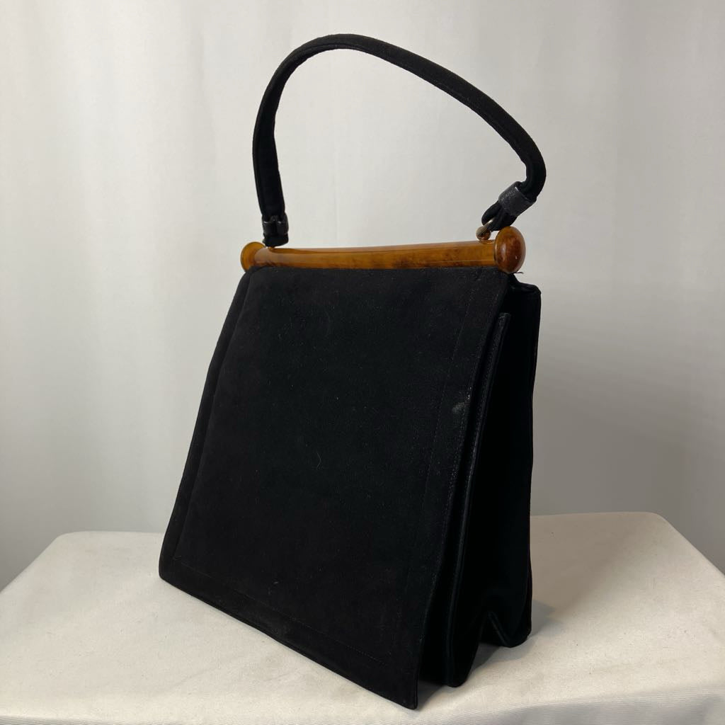Black handbag with a lucite handle on a white surface