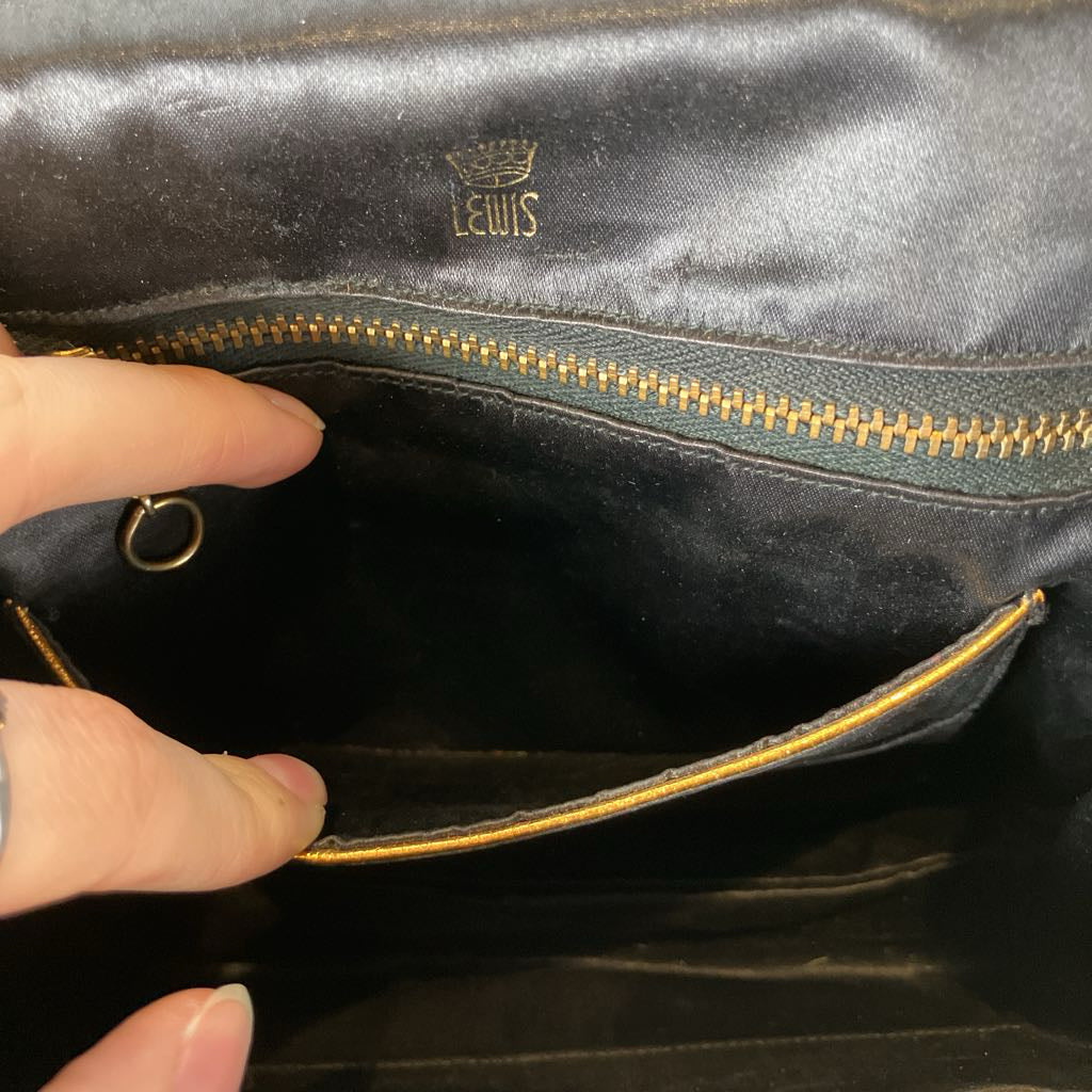 Close-up of a black leather bag with gold zipper and visible brand logo.