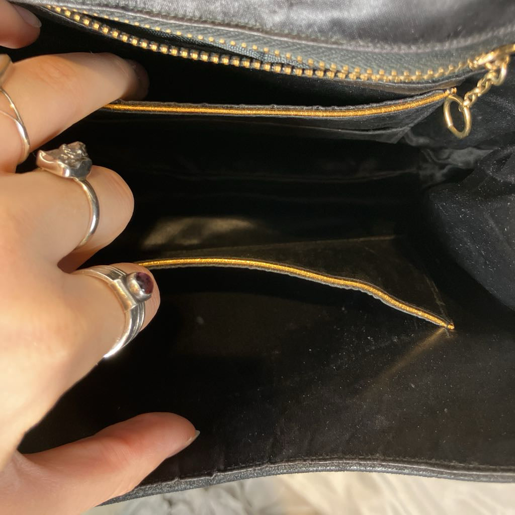 Hand with rings opening a black leather bag